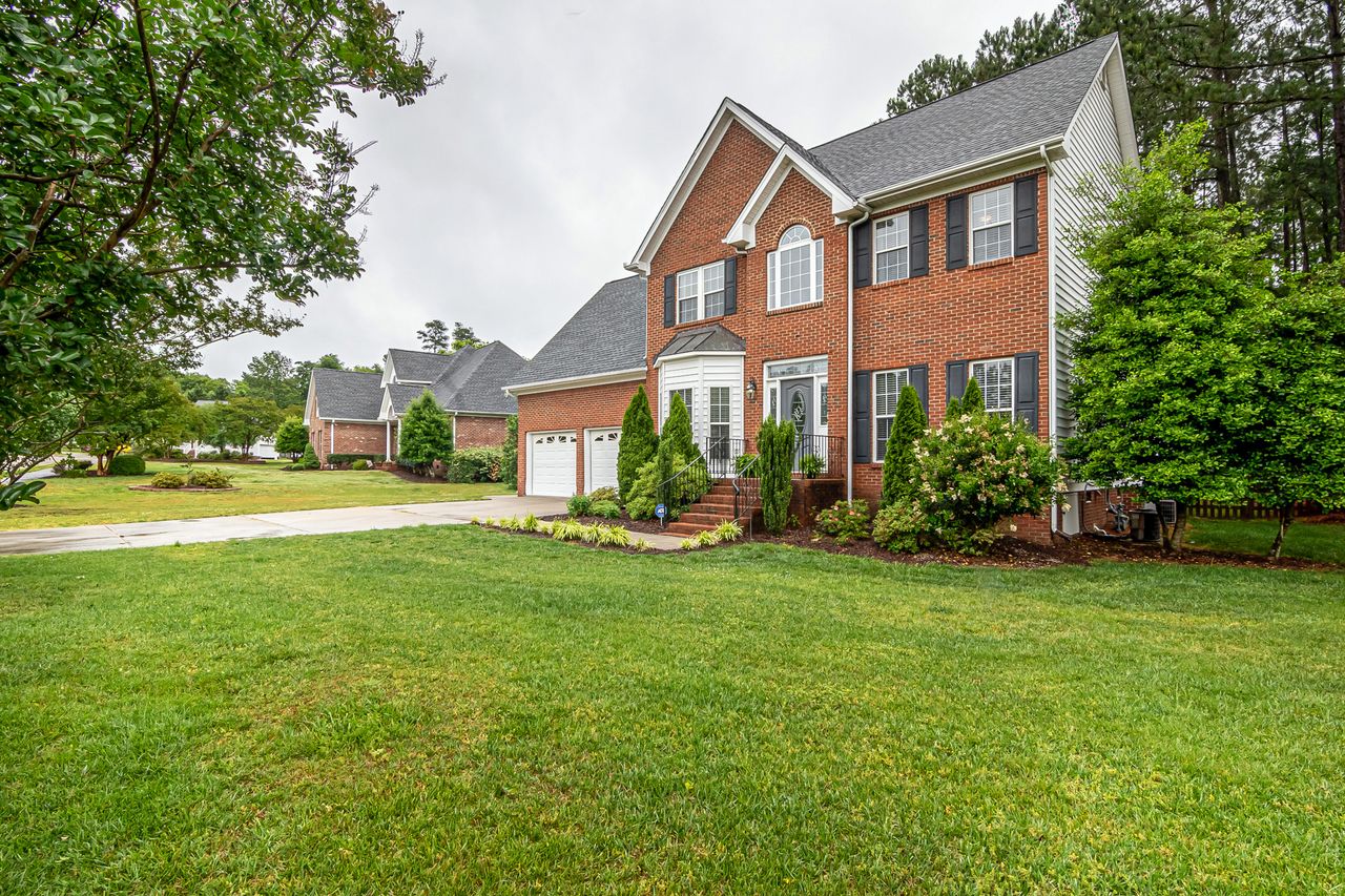 services-02 Charming two-story brick house with manicured lawn and trees, perfect family home.